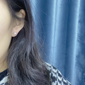 Close-up detail of a minimalist white freshwater pearl stud earring worn by a model
