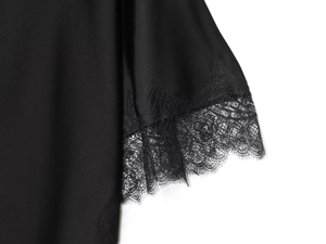 Detail shot of delicate eyelash lace trim on a black silk-like fabric blouse