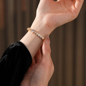 Detailed view of a gold plated flower bangle with sparkling cubic zirconia on a wrist