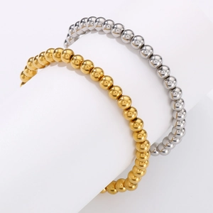 Detailed view of beaded steel bracelets in gold and silver finish on a curved display