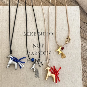 Detailed display of horse tassel necklaces in gold and silver on an artistic book cover