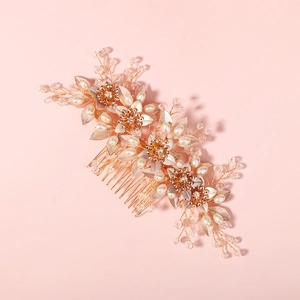 Close-up of golden bridal hair comb with elegant pearls, crystals, and floral metal leaves