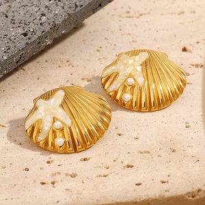Detail of 18K gold starfish shell earrings with pearls on a natural stone base
