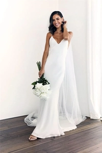 Close-up of minimalist white satin wedding dress with spaghetti straps and long tulle veil