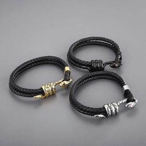 Detailed macro view of woven leather bracelets with snake head clasps and red stone eyes