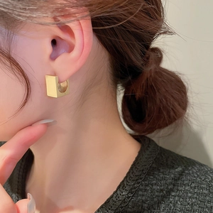 Elegante vergoldete quadratische Creolen an einem Modell für einen stilvollen Look