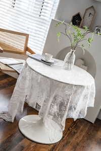 Elegant white lace tablecloth with floral embroidery draped over a tulip round table