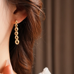 Gros plan de boucles d'oreilles épi de blé dorées avec maillons texturés sur modèle