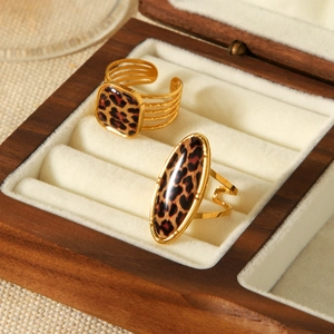 Detail of gold geometric leopard print rings displayed in a luxury wooden jewelry box