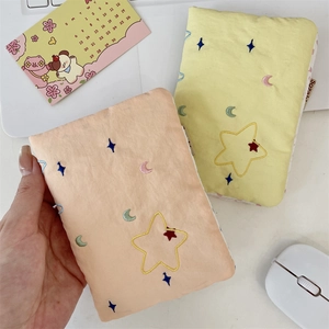 Close-up of star and moon embroidery on fabric passport holder and storage pouch