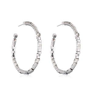 Macro detail of silver geometric hoop earrings with textured square linked pattern