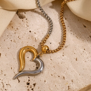 Macro shot of two-tone gold and silver heart pendant on a stone and silk background