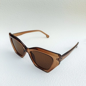 Detail shot of vintage cat-eye sunglasses with amber frames and brown lenses at 45-degree angle