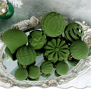 Close-up of green flocked Christmas balls in diverse shapes on a vintage mirror tray