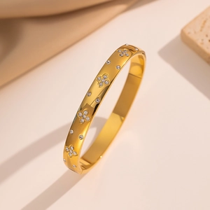Elegant gold plated stainless steel bangle featuring sparkling clover motifs with crystals