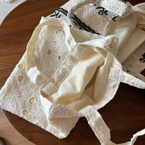 Detailed close-up of vintage lace embroidery and hollow eyelet patterns on cotton handbags
