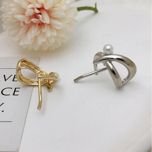Detail view of intertwined metal earrings with pearls in gold and silver finish