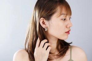 Close-up of a silver-finished C-shaped earring worn by a model in a minimalist style