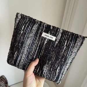 Detail of woven fabric handbag featuring blue and black stripes with a simple wish label