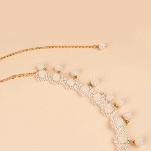 Close-up of golden chain belt featuring woven pearl flowers and hanging pearl pendants