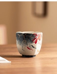 Detail of hand-painted koi fish and lotus on a hexagonal ceramic teacup with gold edges