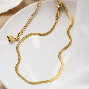 Luxurious gold snake bone necklace for women with heart pendant on a white ceramic tray