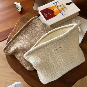Close-up of beige tweed cosmetic bags with zipper and simple wish label on wooden table