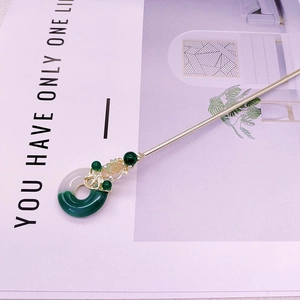 Détail macro du pendentif en jade vert foncé et de la feuille dorée sur le pic à cheveux