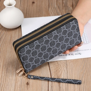 Detail of a double zipper long wallet with clover pattern and detachable wrist strap