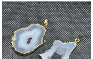 Dettaglio macro di pendenti in geode di agata naturale con bordi placcati oro 14K e cristalli