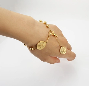Gros plan d'un bracelet à perles plaqué or 18K avec médailles religieuses au poignet