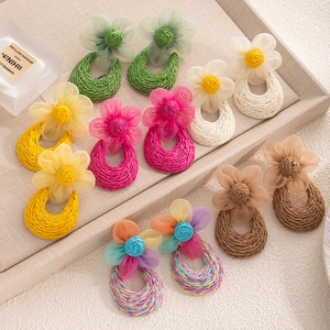 Flat lay view of colorful handmade raffia flower earrings in bohemian summer style