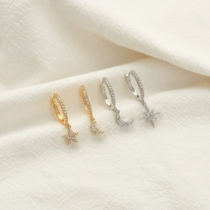 Close-up of asymmetric gold and silver star and moon huggie earrings with zircon