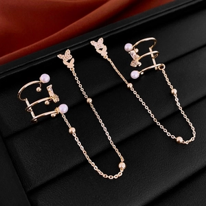 Elegant gold butterfly ear cuff with long chains, pearls, and zircons on silk background