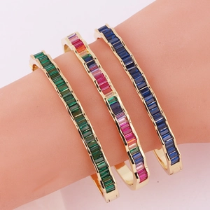 Detail of 18k gold plated wave bangles with emerald, rainbow, and navy blue rectangle stones
