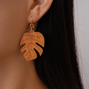 Detail shot of a monstera leaf wooden earring with natural grain and gold hook