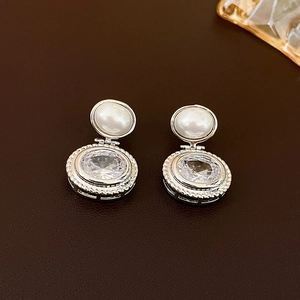 Detailed macro view of vintage silver earrings featuring pearls and oval cubic zirconia stones