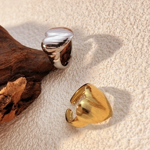 Minimalist heart-shaped stainless steel rings in gold and silver finish on wood