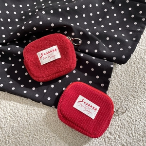 Detail of red corduroy and fleece coin pouches with zipper rings and woven label labels