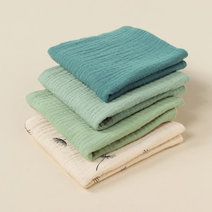 Detail of 4-pack stacked cotton muslin washcloths in solid colors and dandelion print
