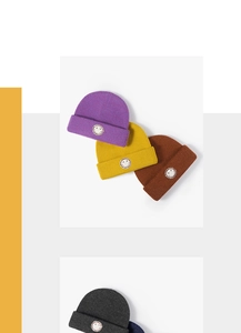 Detail of colorful knitted beanies with smiley face patch on white display blocks