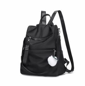 Detail of black nylon backpack with secure back-opening and white pom-pom pendant