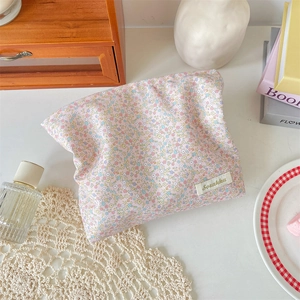 Detailed top view of a cotton floral makeup bag with pink flower patterns on a wooden desk