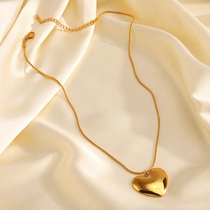 Polished gold stainless steel heart pendant necklace on an elegant silk background