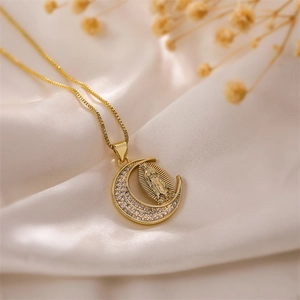 Detail shot of a gold heart moon necklace with Virgin Mary relief on white silk
