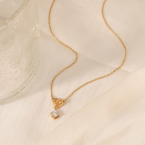 Elegant gold heart pendant necklace with clear zircon on beige textured fabric
