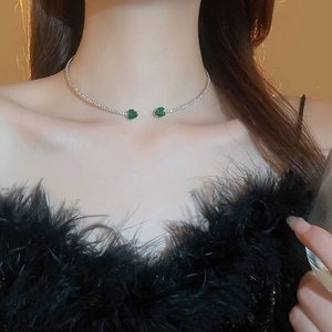 Detailed view of silver choker featuring two green heart-shaped gemstones on collar