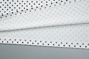 Dettaglio del tessuto bianco a pois neri che mostra le cuciture di qualità e la trama