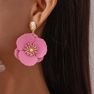 Close-up of pink flower petal earrings with gold texture and white pearl center on model