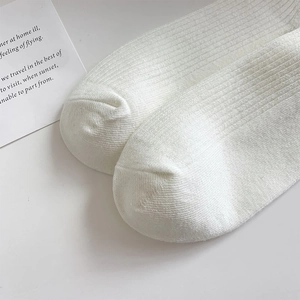 Close-up of white ribbed cotton socks featuring fine vertical knit texture and soft fabric